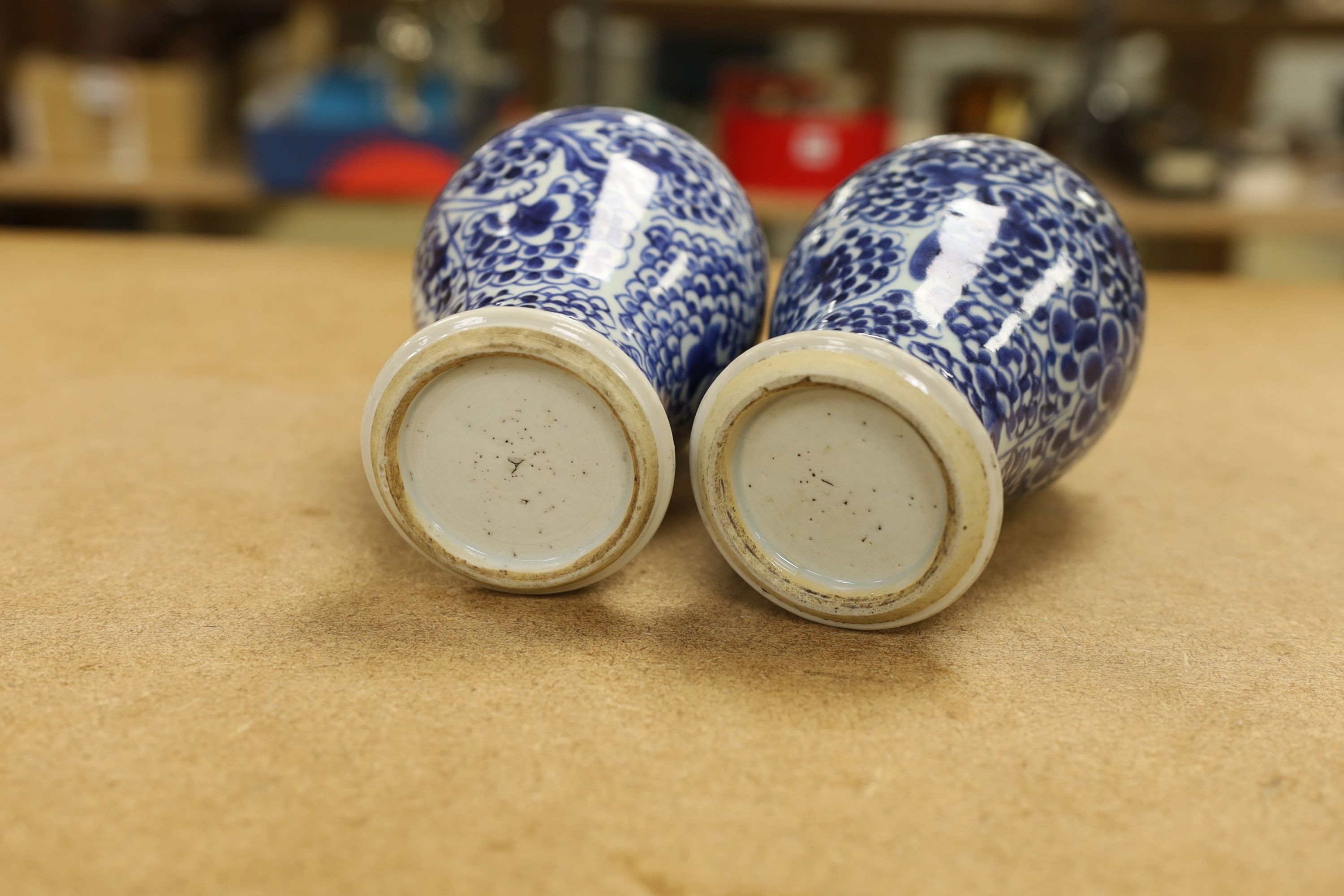 A pair of Chinese blue and white 'phoenix' vases, Kangxi, associated wood covers, 19cm including covers